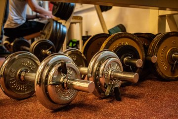Mehrere Hanteln liegen auf dem Boden des Fitnessraums