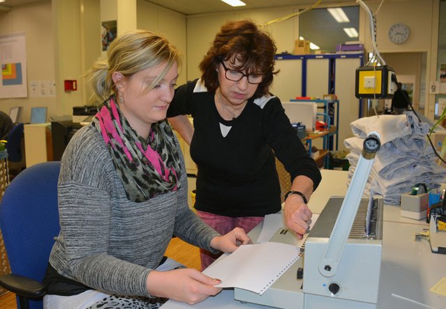 Auszubildende bekommt das Plastikbindegerät erklärt