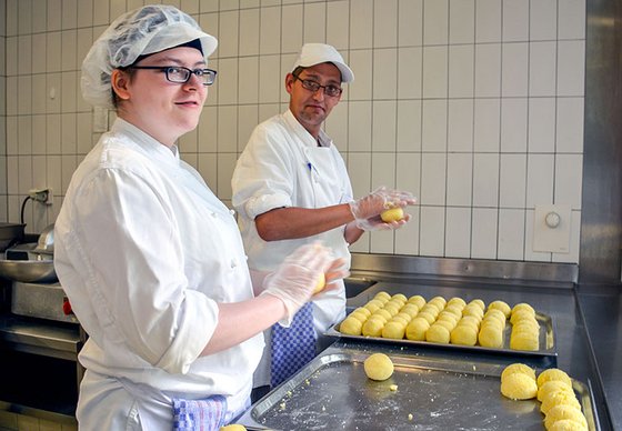 Zwei junge Köche formen Kartoffelklöße.