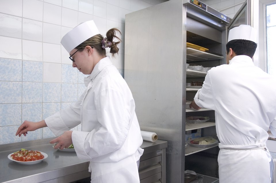 Köchin garniert ein Gericht in der Küche. 