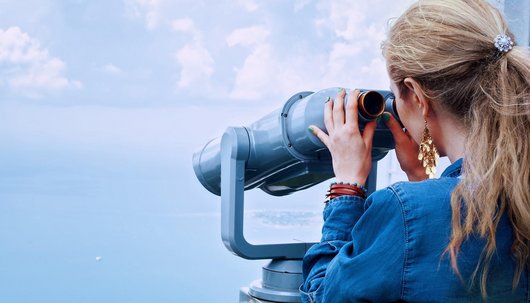 Schmuckbild: Junge Frau schaut durch ein Fernrohr