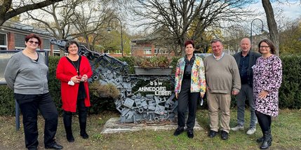 Mehrere Menschen stehen vor einer Skulptur mit dem Schriftzug "Annedore-Leber-BBW"