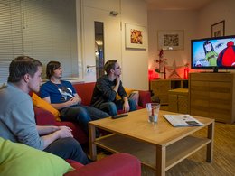 Junge Menschen sitzen auf dem Sofa und schauen fern.