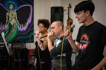 Drei Auszubildende singen mit Mikrophonen 