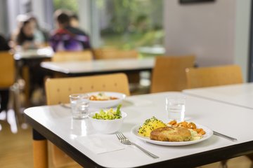 Zwei Essensteller mit verschiedenen Gerichten auf einem Tisch in der Mensa