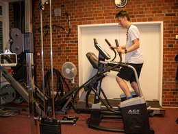 Ein junger Mann trainiert an einem Fitnessgerät.