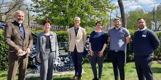 Zwei Frauen und drei Männer stehen vor einer Metallskulptur des ALBBW
