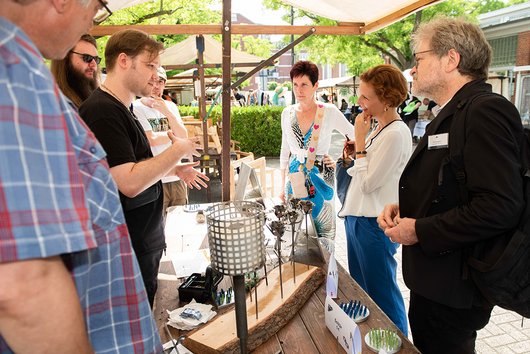 Mehrere Menschen besuchen einen Marktstand.