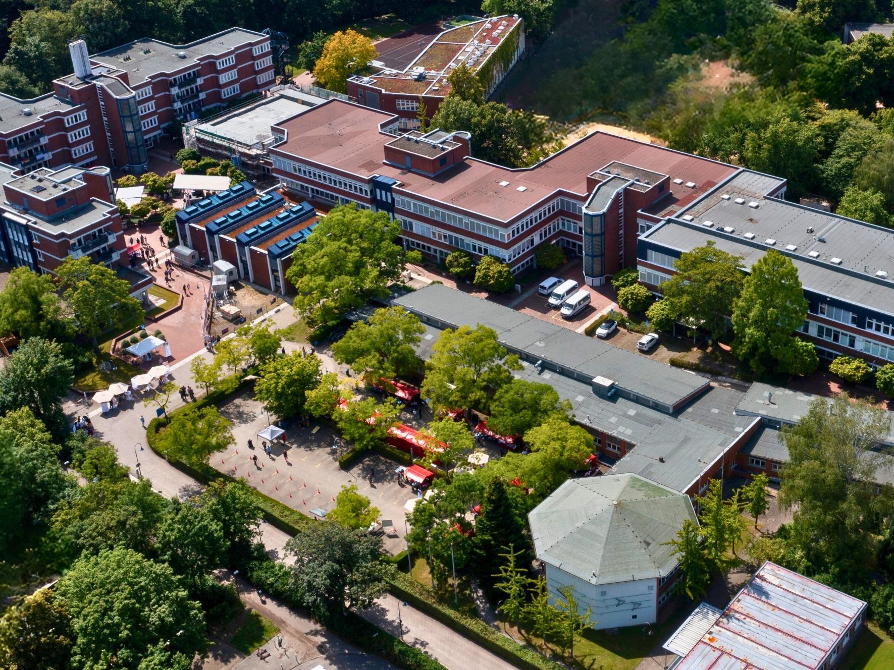 Es sind mehrere Gebäude des ALBBW aus einer Luftaufnahme zu sehen. Es ist Sommer und die Bäume sind mit grünen Blättern bewachsen 