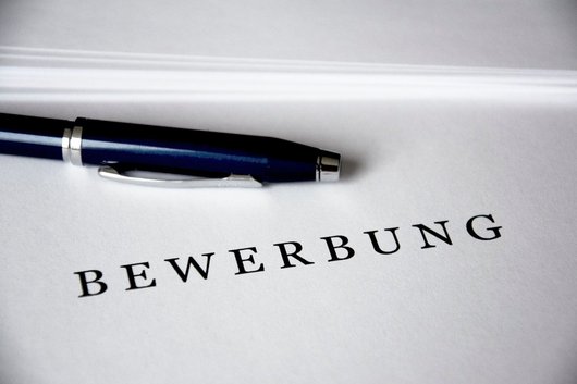 Ein Blatt Papier mit dem Schriftzug "Bewerbung" und ein Kugelschreiber