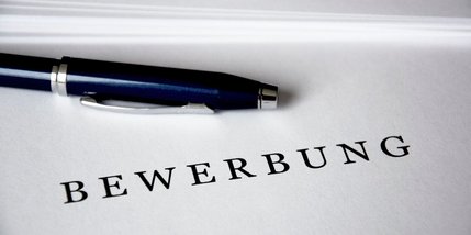 Ein Blatt Papier mit dem Schriftzug "Bewerbung" und ein Kugelschreiber