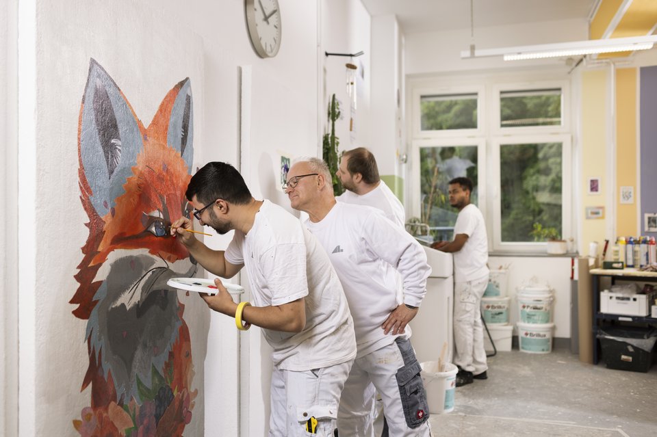 Drei Auszubildende beim Malern mit Ausbilder