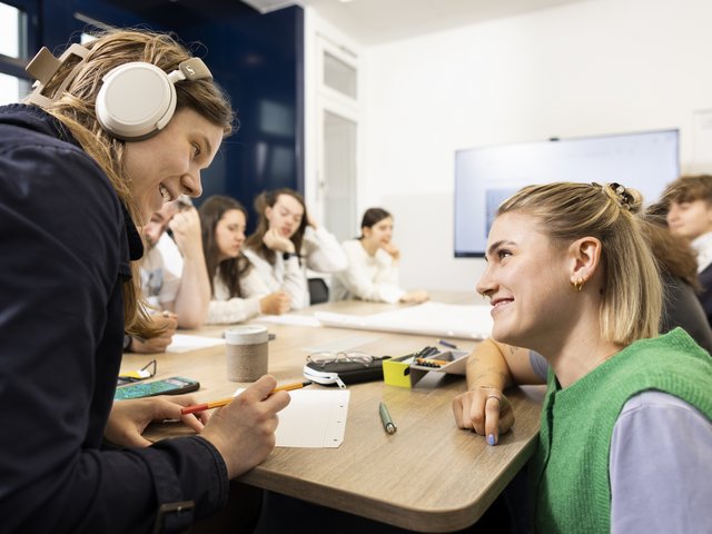 Mitarbeiterin hilft Auszubildenden an einem Gruppentisch