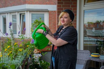 Eine Auszubildende gießt Blumen auf dem Balkon