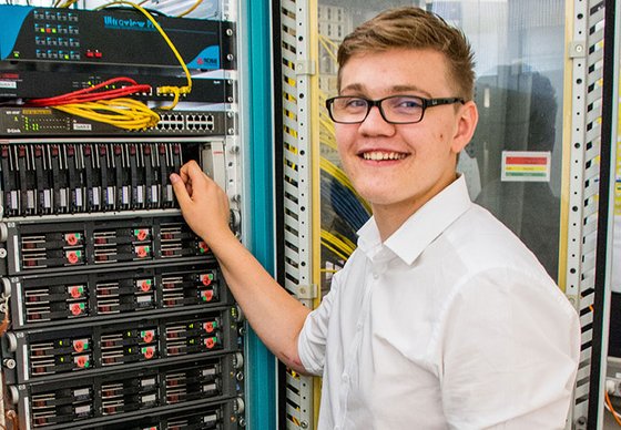 Ein junger Mann arbeitet an einem Serverschrank.