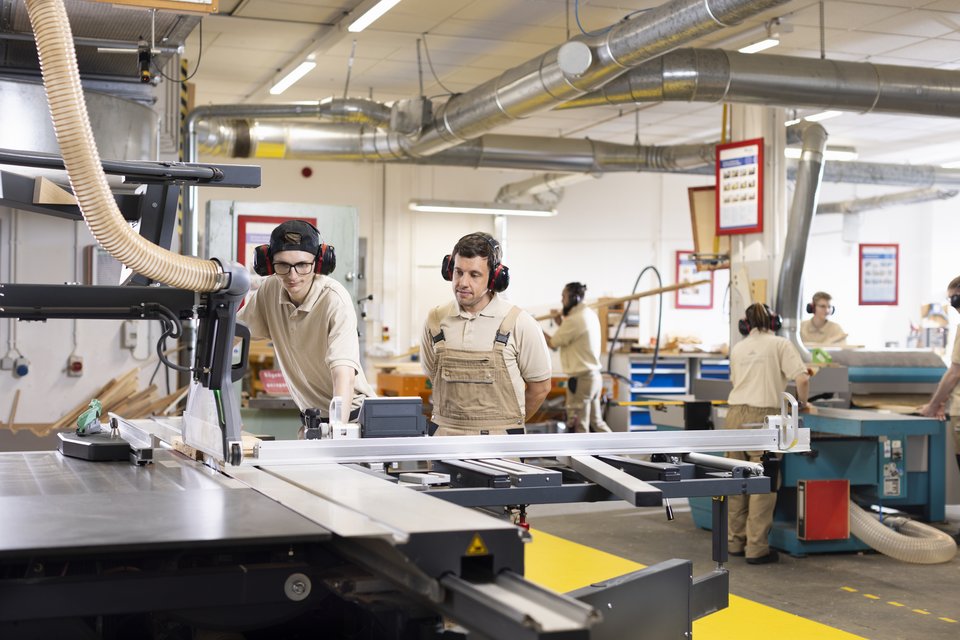 Auszubildende und ein Ausbilder in der Holzwerkstatt