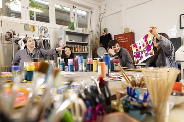 Vier Auszubildende arbeiten mit Farben an einem großen Tisch