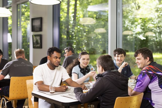 Fünf Auszubildende an einem Tisch in der Mensa beim Mittagessen