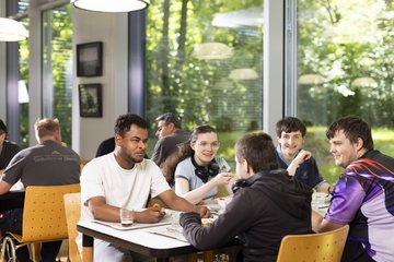 Fünf Auszubildende an einem Tisch in der Mensa beim Mittagessen