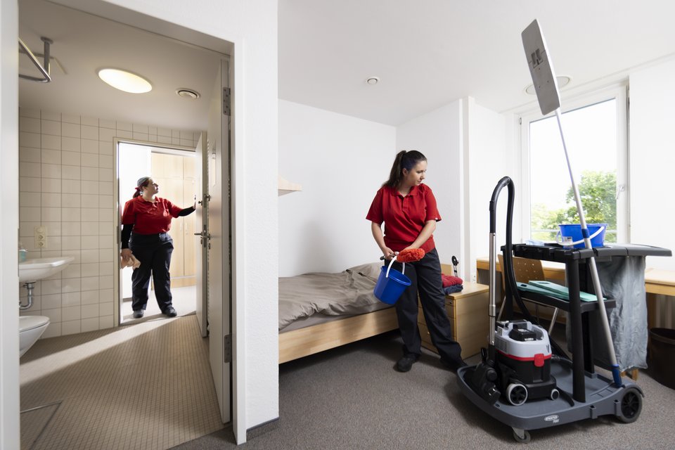 Zwei Auszubildende reinigen ein Internatszimmer