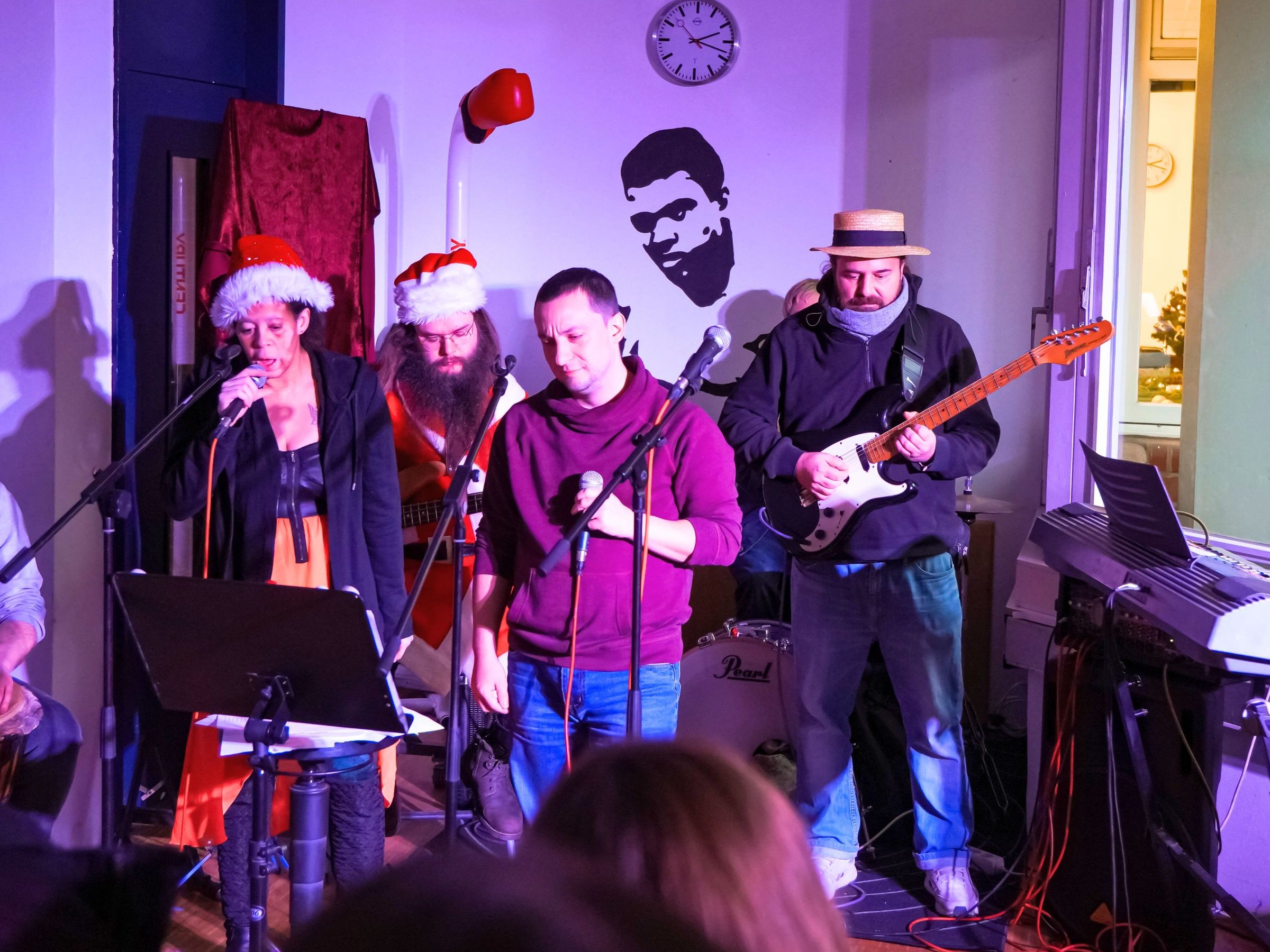 Vier Personen machen Musik, zwei davon haben Weihnachtsmützen auf