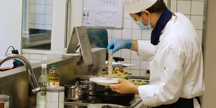 Junger Koch arbeitet am Herd