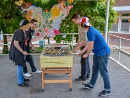 Vier junge Menschen spielen Tischkicker.