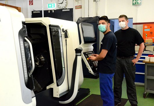 Zwei Männer an einer CNC-Maschine