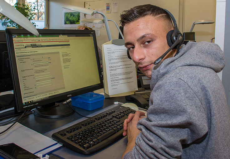 Junger Mann mit Headset an einem PC