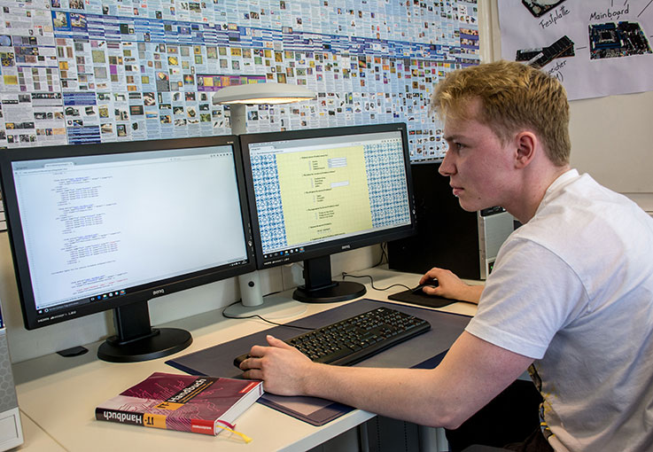 Ein Auszubildender sitzt an seinem Computerbildschirm und programmiert.
