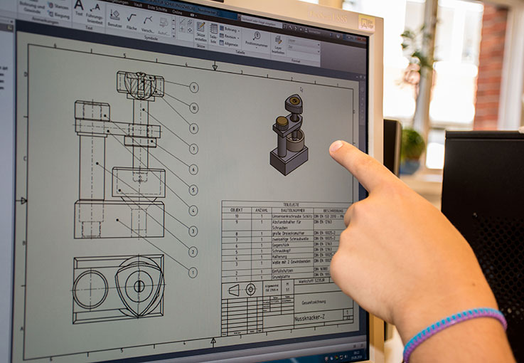 Eine Hand zeigt auf einen Monitor mit einer Konstruktionszeichnung