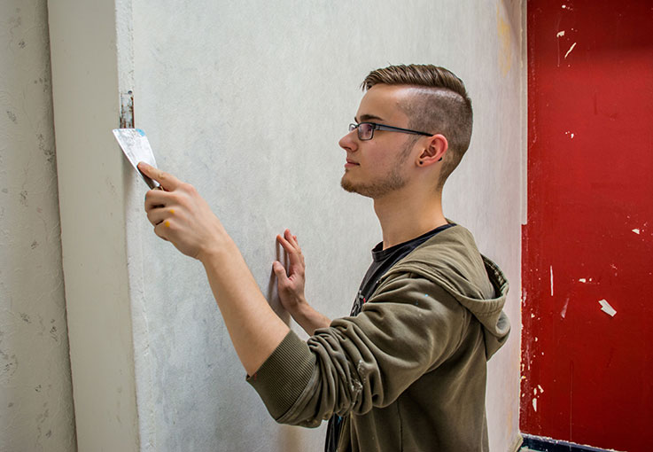 Auszubildender verspachtelt einen Türrahmen.