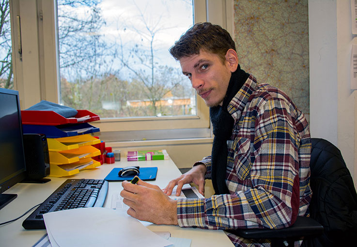 Auszubildender sitzt an Schreibtisch und macht Notizen