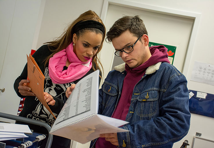 Zwei Auszubildende schauen gemeinsam in Unterlagen und planen das nächste Projekt.