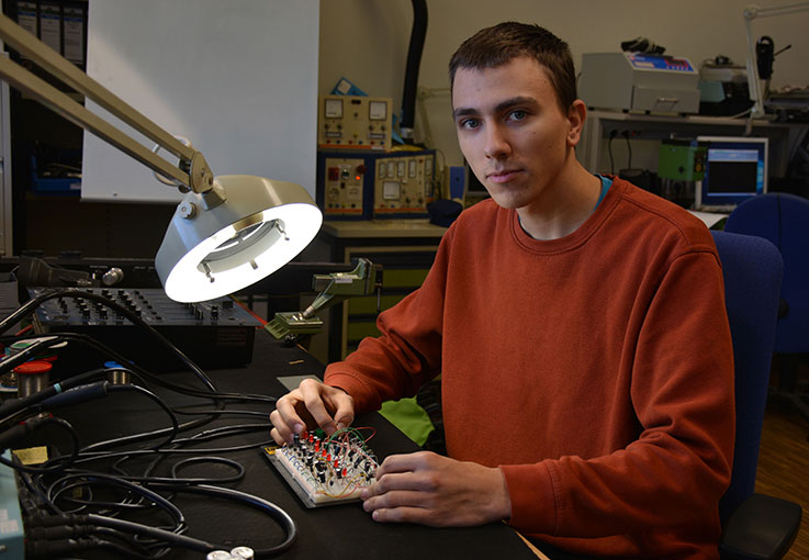 Ein Auszubildender der eine Platine verkabelt.