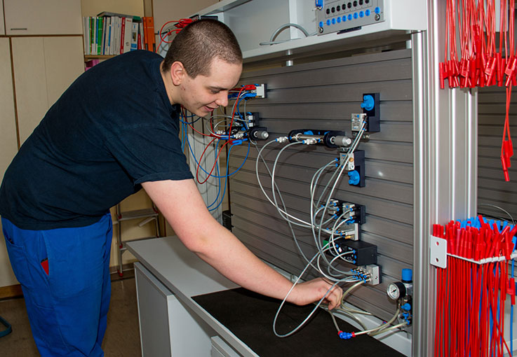 Ein junger Mann baut eine pneumatische Schaltung auf