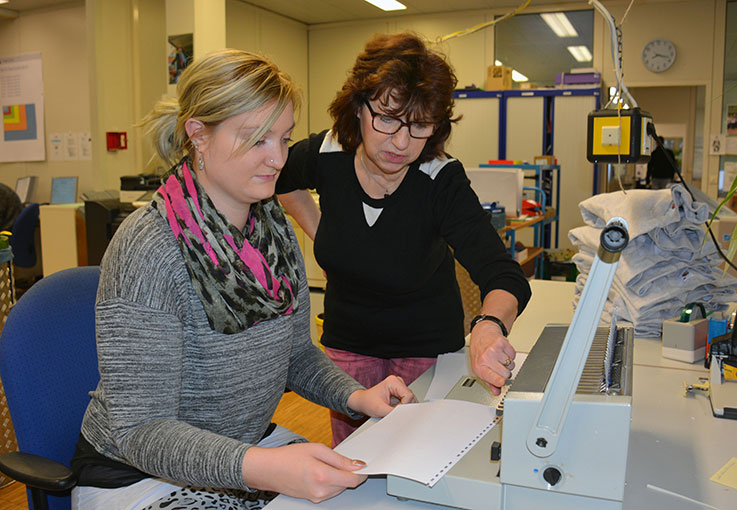 Auszubildende bekommt das Plastikbindegerät erklärt