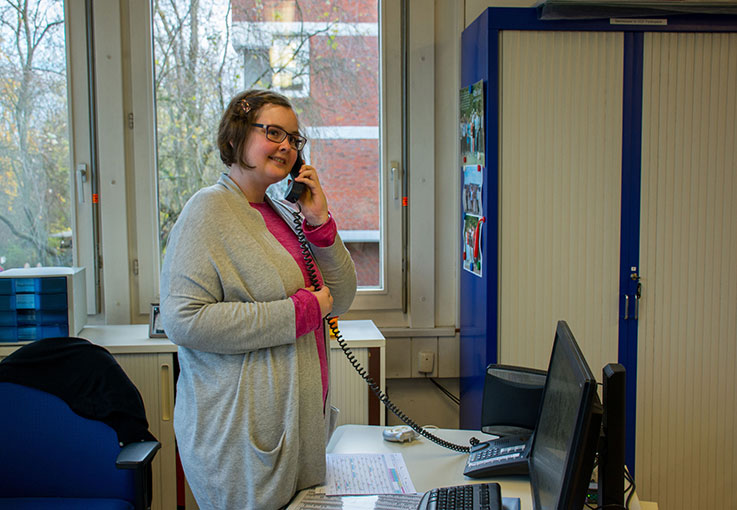 Eine Auszubildende beantwortet das Telefon in einem Büro.