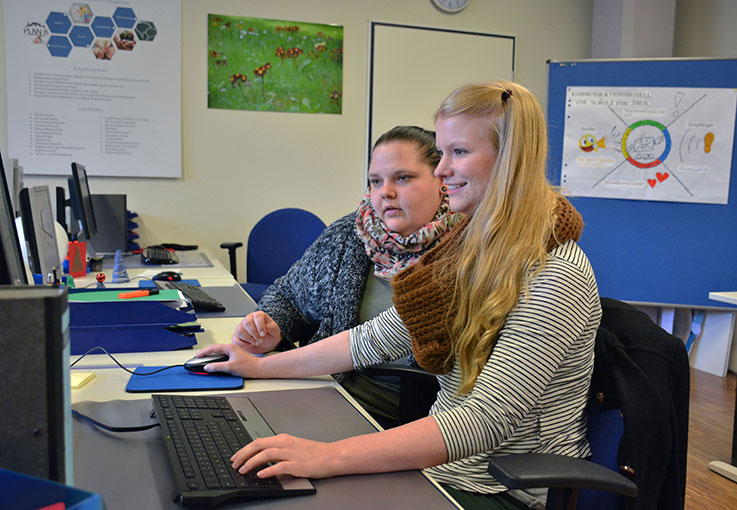 Zwei Auszubildende an einem Computer.